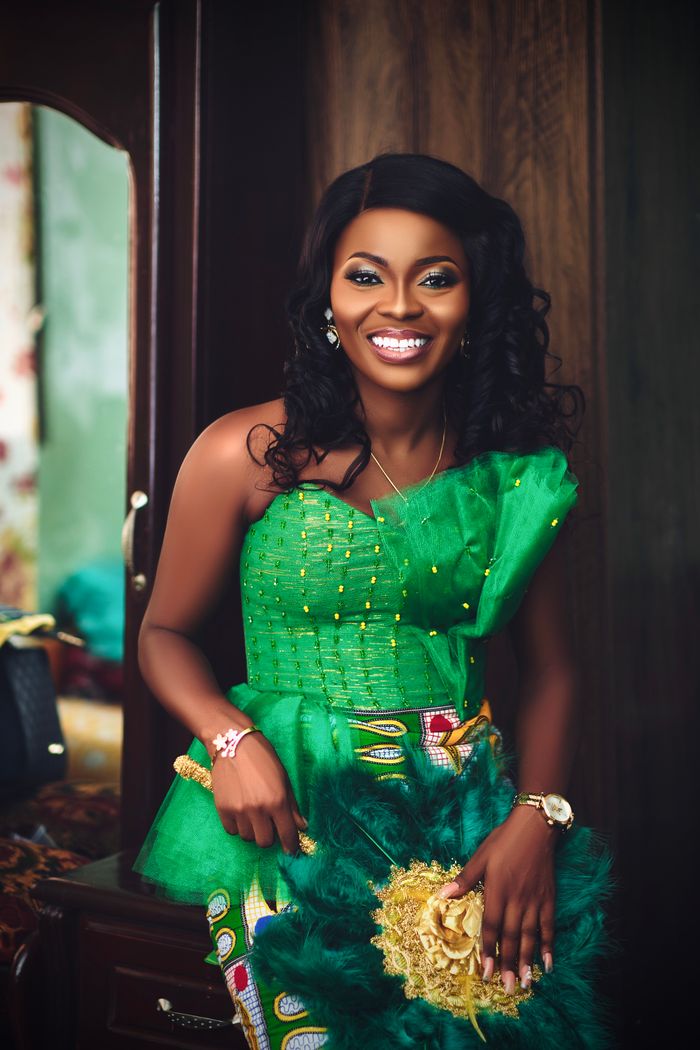 Smiling woman in vibrant green traditional dress, Accra, Ghana.
