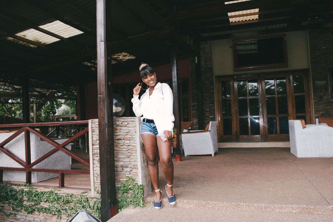 Confident woman in casual wear posing and smiling at an outdoor resort in Accra, Ghana.