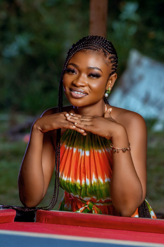 A woman in a colorful dress smiling outdoors, showcasing natural beauty.
