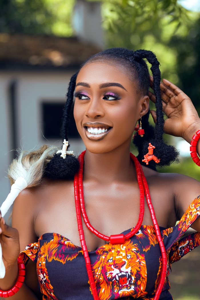 Woman in colorful Ghanaian attire celebrating cultural heritage outdoors.