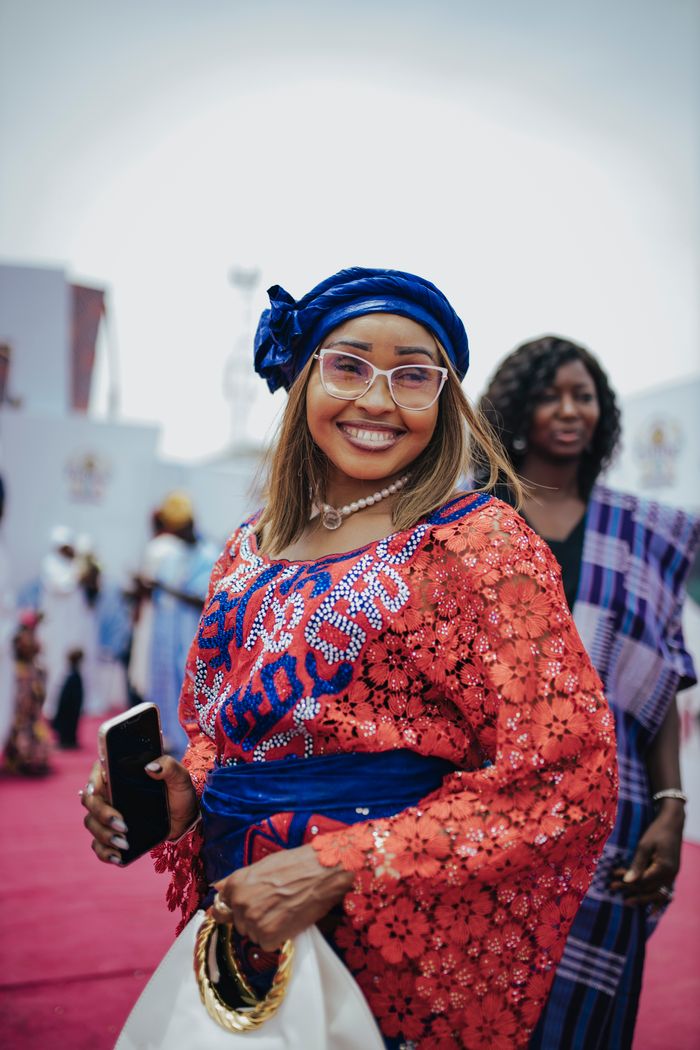 Woman in colorful traditional African attire at an outdoor gathering.